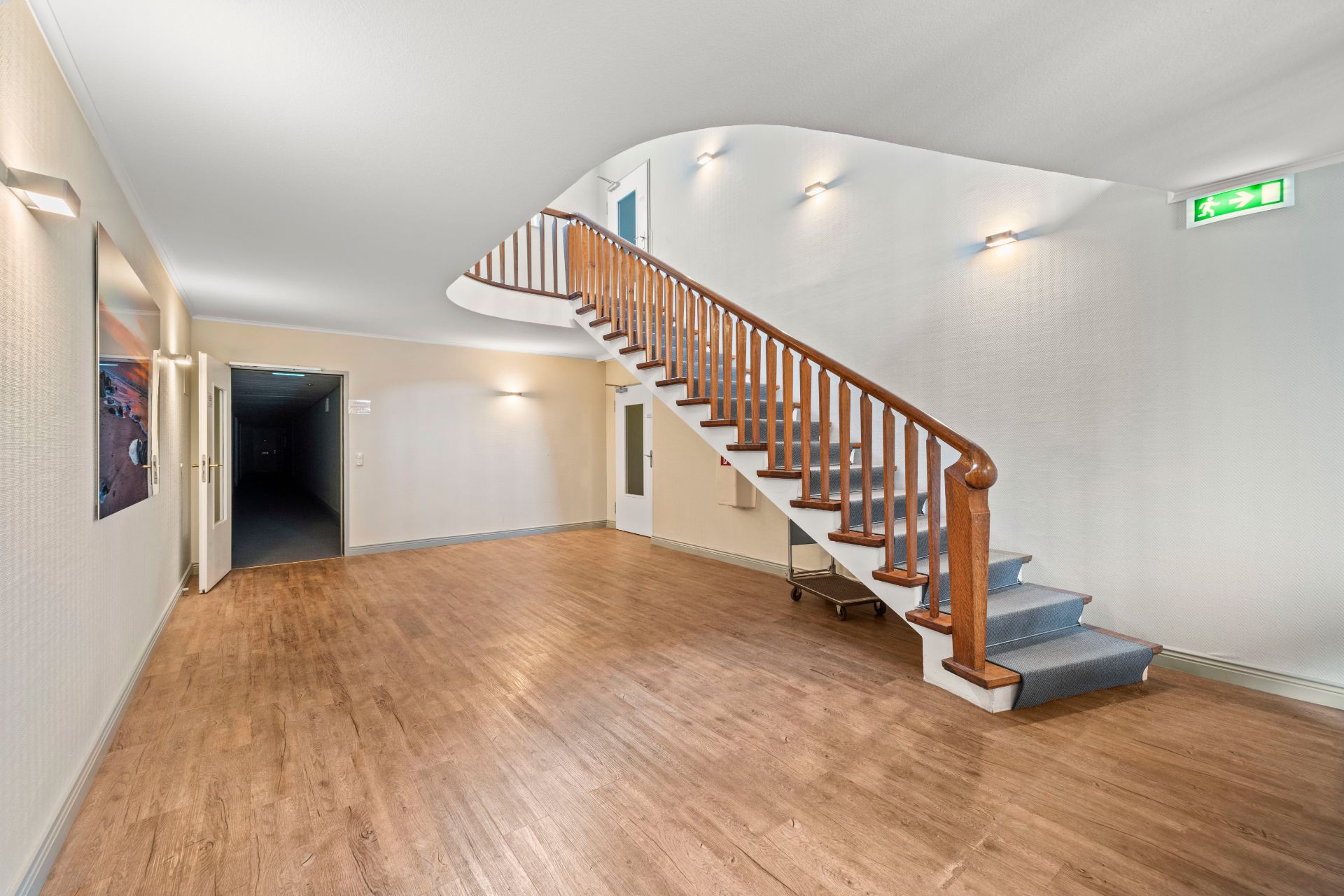 Heller Flur mit Holztreppe, Holzfußboden und Wandbeleuchtung.