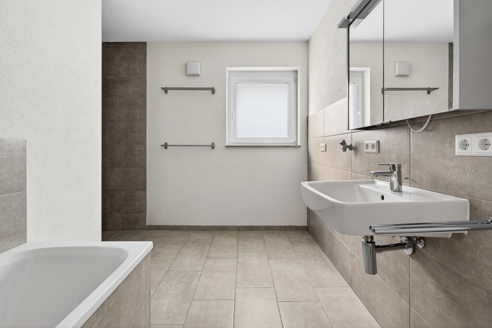Modernes Badezimmer mit Badewanne, großem Waschbecken, Spiegel und Fenster.