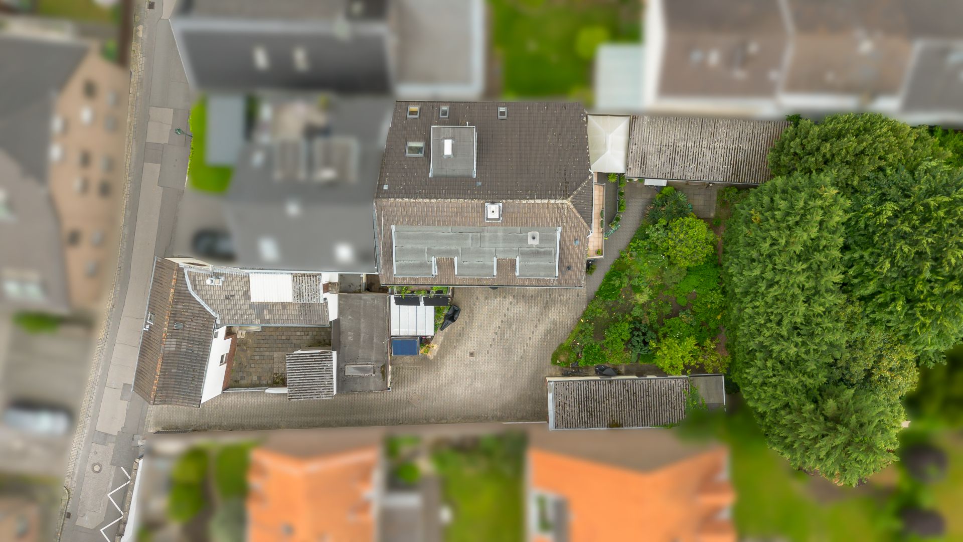 Luftaufnahme eines Wohnhauses mit Garten und Einfahrt, umgeben von anderen Häusern.