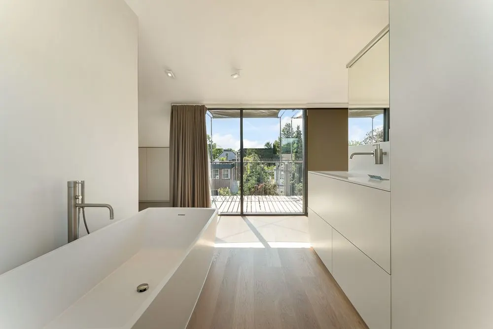Modernes Badezimmer mit freistehender Badewanne und großem Fenster zum Balkon.
