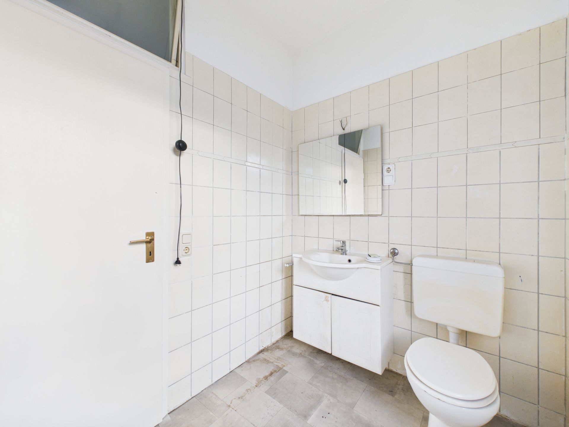 Helles Badezimmer mit weißer Toilette, Waschbecken, Spiegel und gefliesten Wänden.