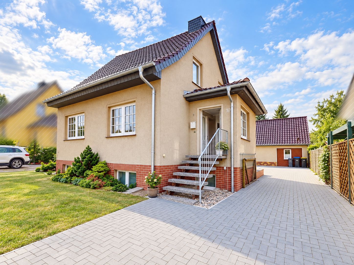 Einfamilienhaus mit Garten, gepflastertem Weg und Außentreppe zum Eingang.