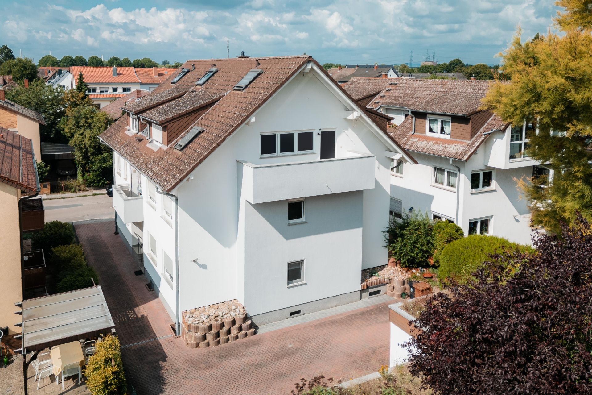Modernes, weißes Wohnhaus mit Satteldach, mehreren Fenstern und gepflegtem Hof.