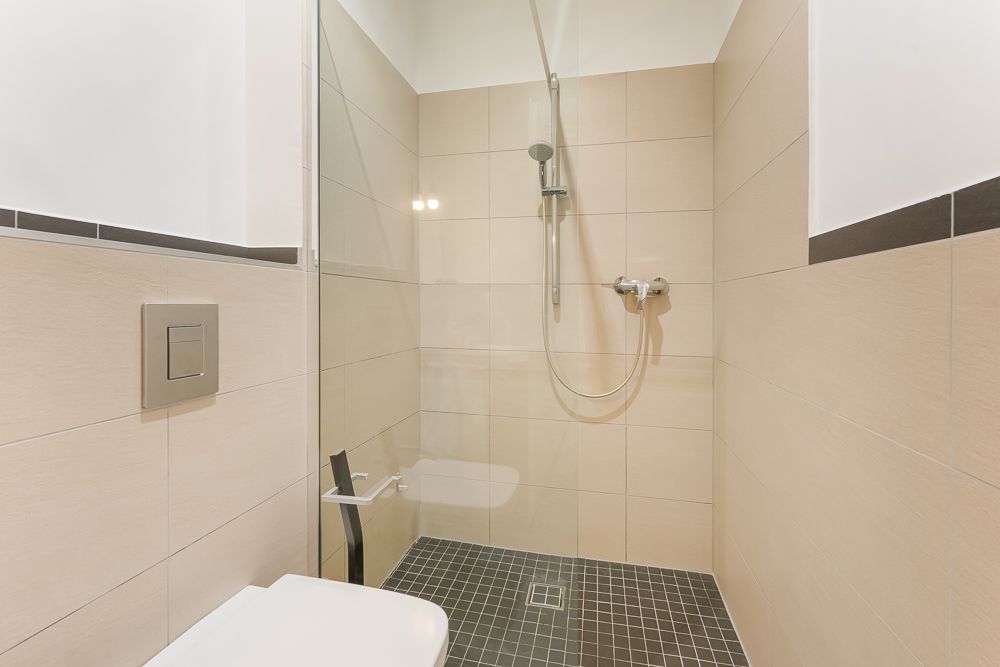Modernes Bad mit begehbarer Dusche, Glaswand und hellen Fliesen.