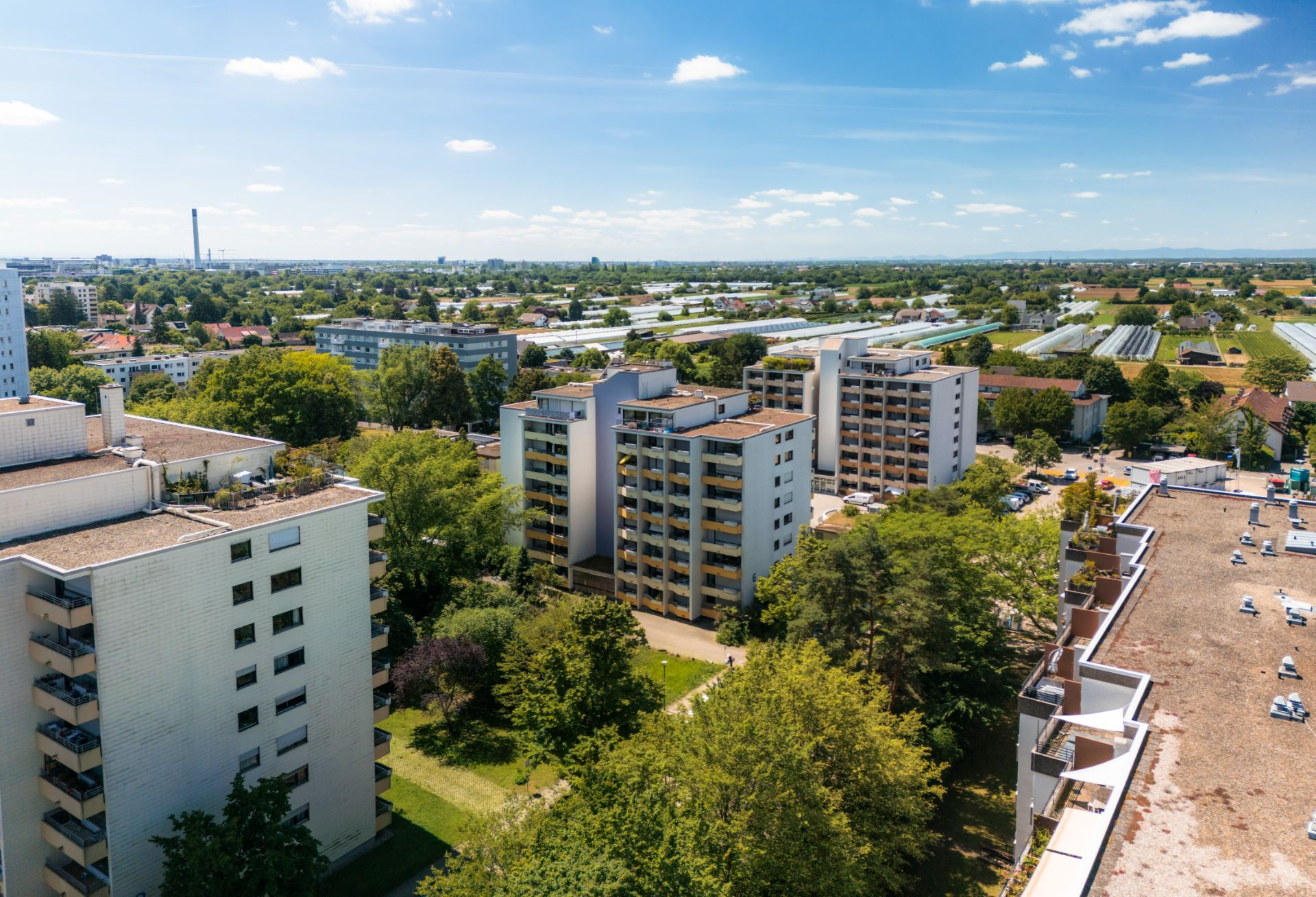 Mehrere Wohngebäude mit Balkonen und viel Grünfläche sind aus der Vogelperspektive sichtbar.