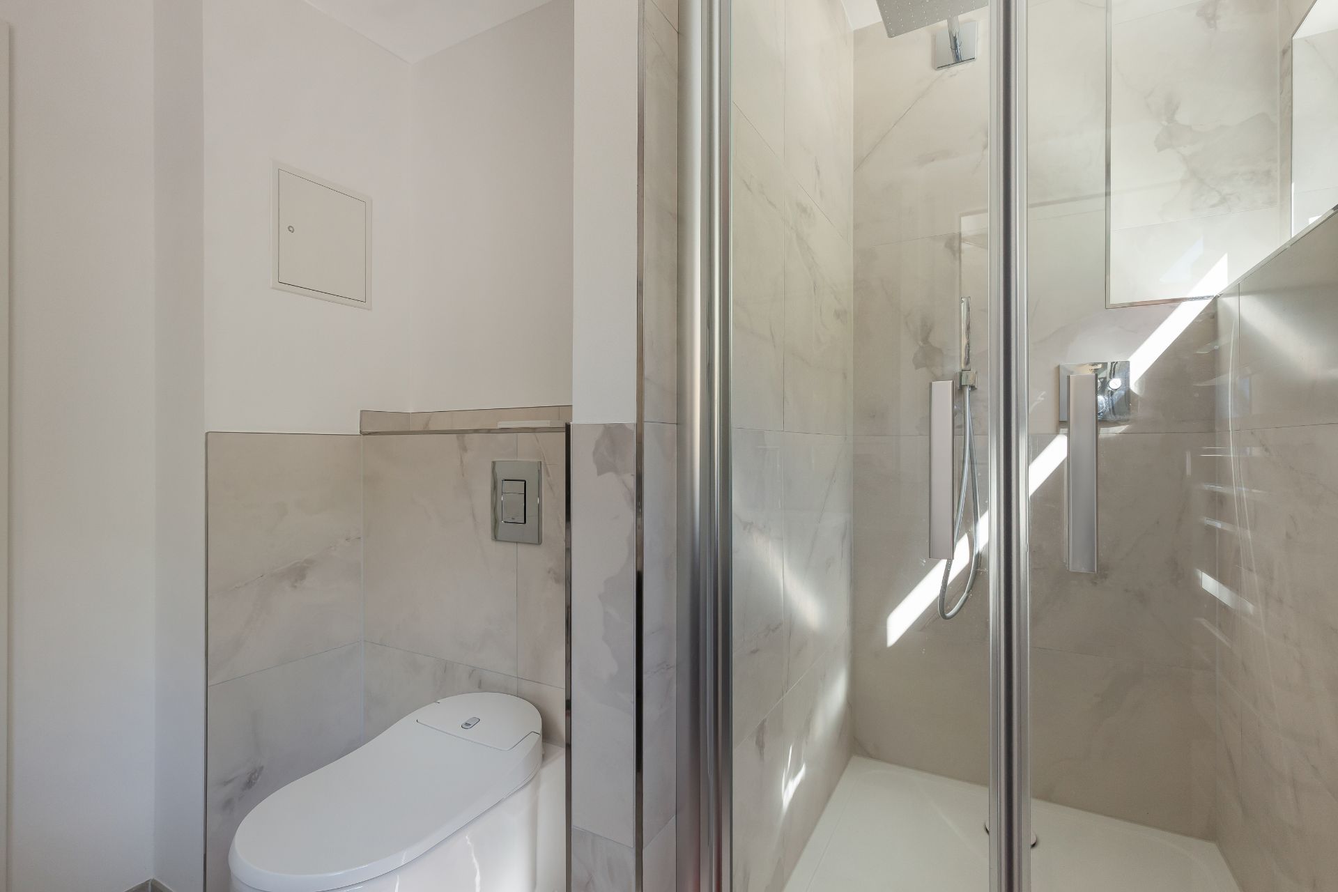 Modernes Badezimmer mit Toilette und einer Duschecke mit Glastür.