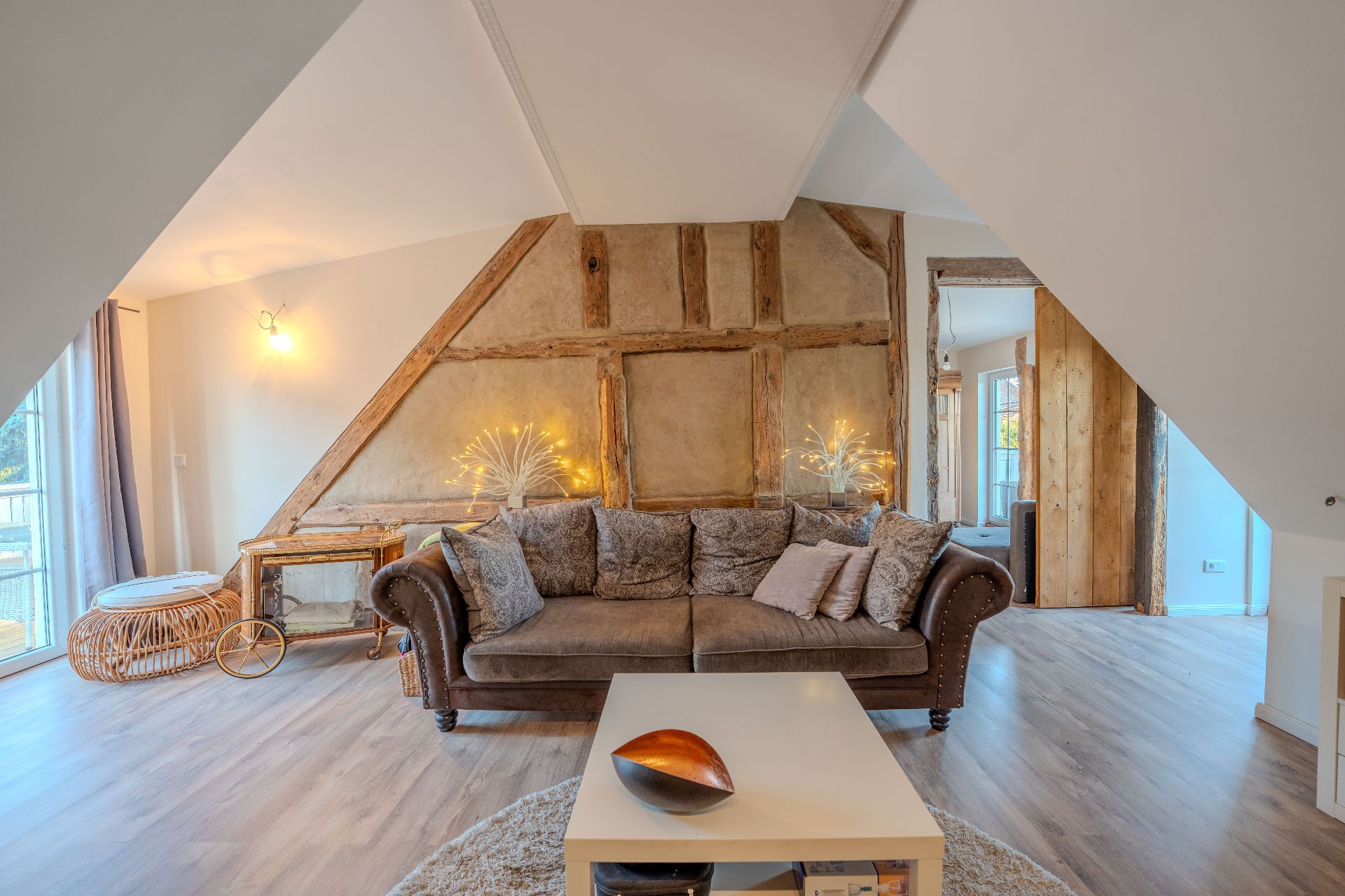 Wohnzimmer mit braunem Sofa, Couchtisch, Holzdekor und dekorativen Lampen an der Wand.