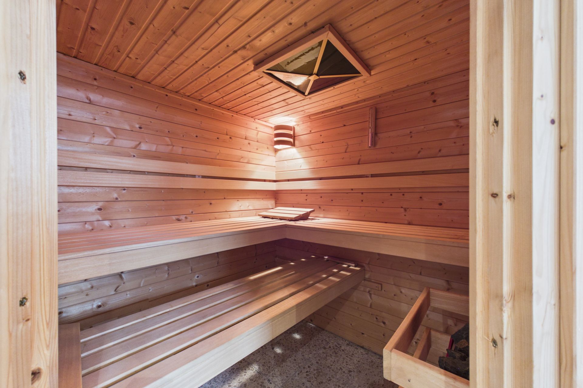 Holzsauna mit Bänken und einer Lampe an der Wand.