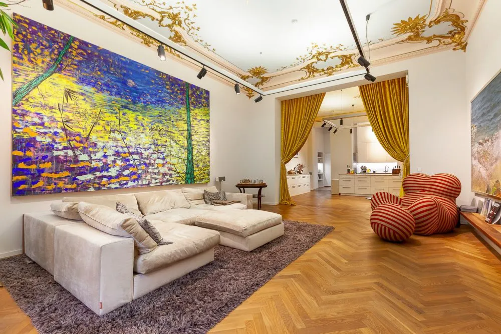 Modernes Wohnzimmer mit großem Sofa, buntem Gemälde und goldenen Vorhängen, Parkettboden.