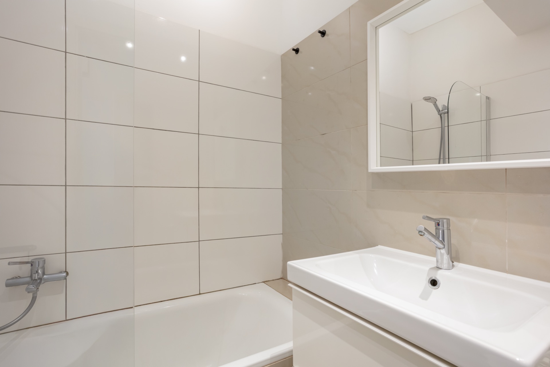 Helles Badezimmer mit Badewanne, Waschbecken und Spiegel.