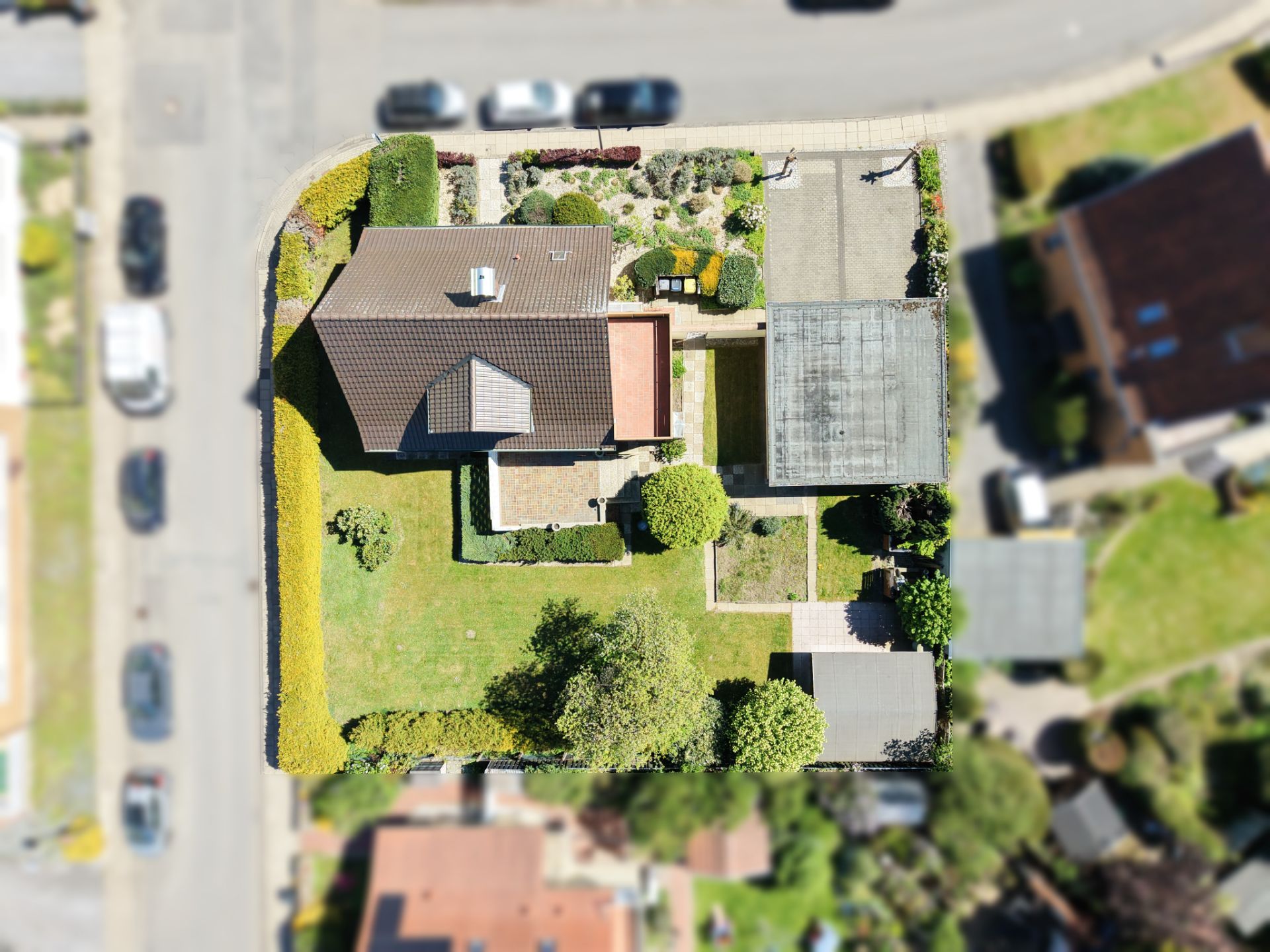 Luftaufnahme eines Einfamilienhauses mit Garten, Auffahrt und Garage in einem Wohngebiet.