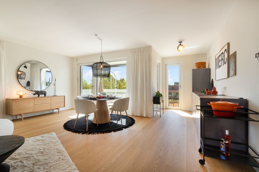 Helles Wohnzimmer mit Esstisch, großem Fenster, Holzfußboden und moderner Einrichtung.