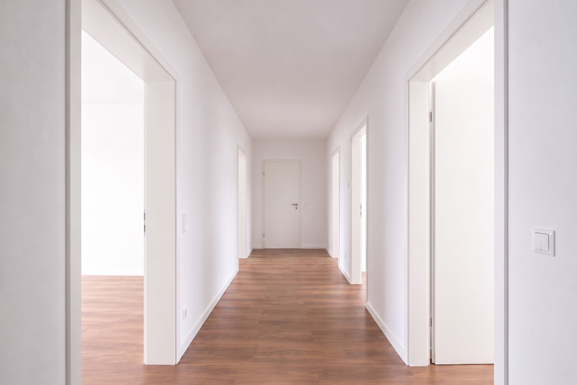 Heller Flur mit Holzboden und weißen Türen in einer Wohnung.
