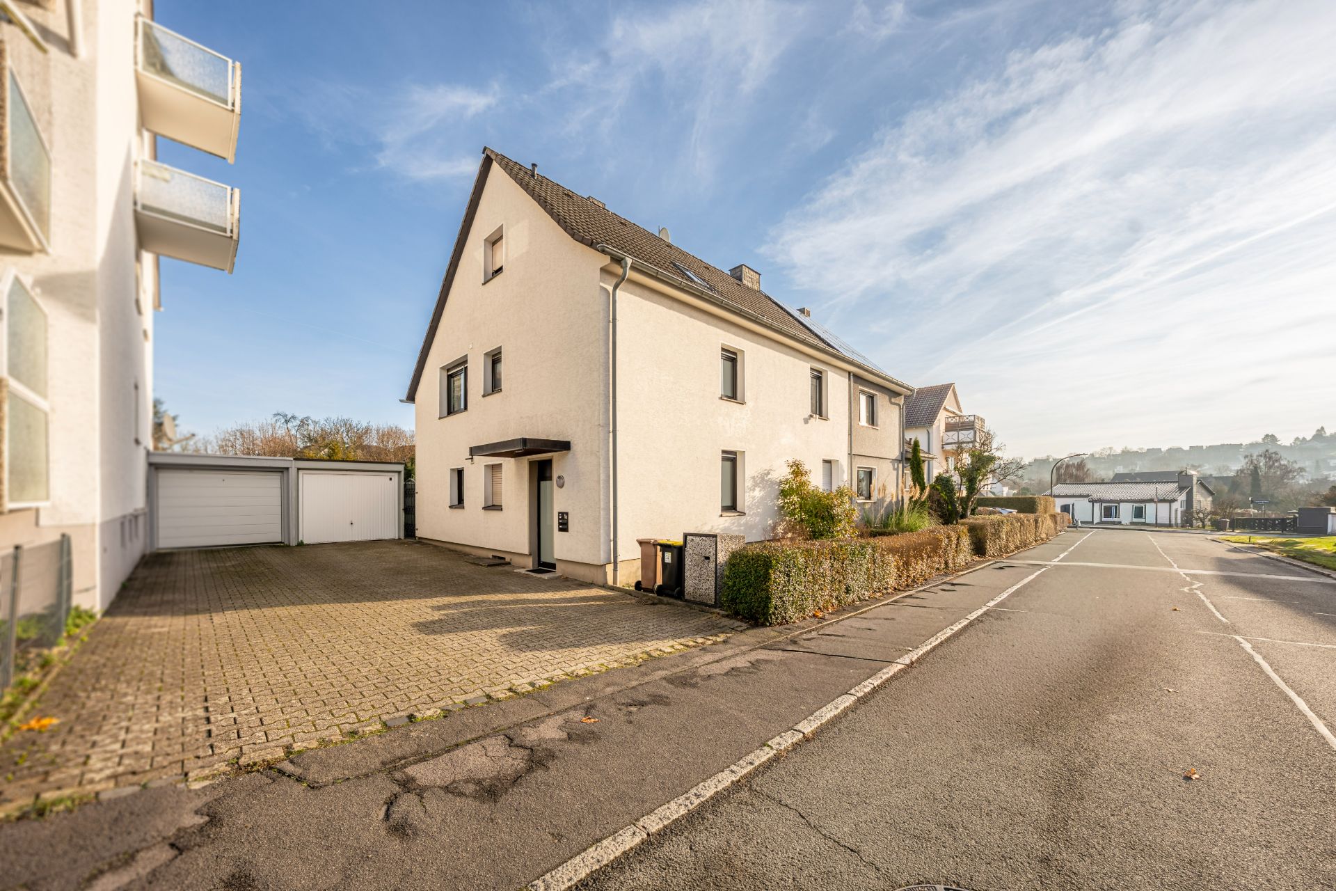 Zweistöckiges Wohnhaus mit Einfahrt und Garage an einer ruhigen Straße.