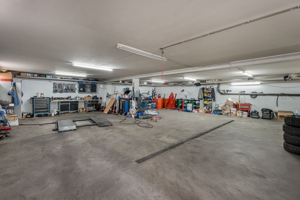 Große Garage mit Werkbänken, Werkzeugen und verschiedenen Materialien an den Wänden.