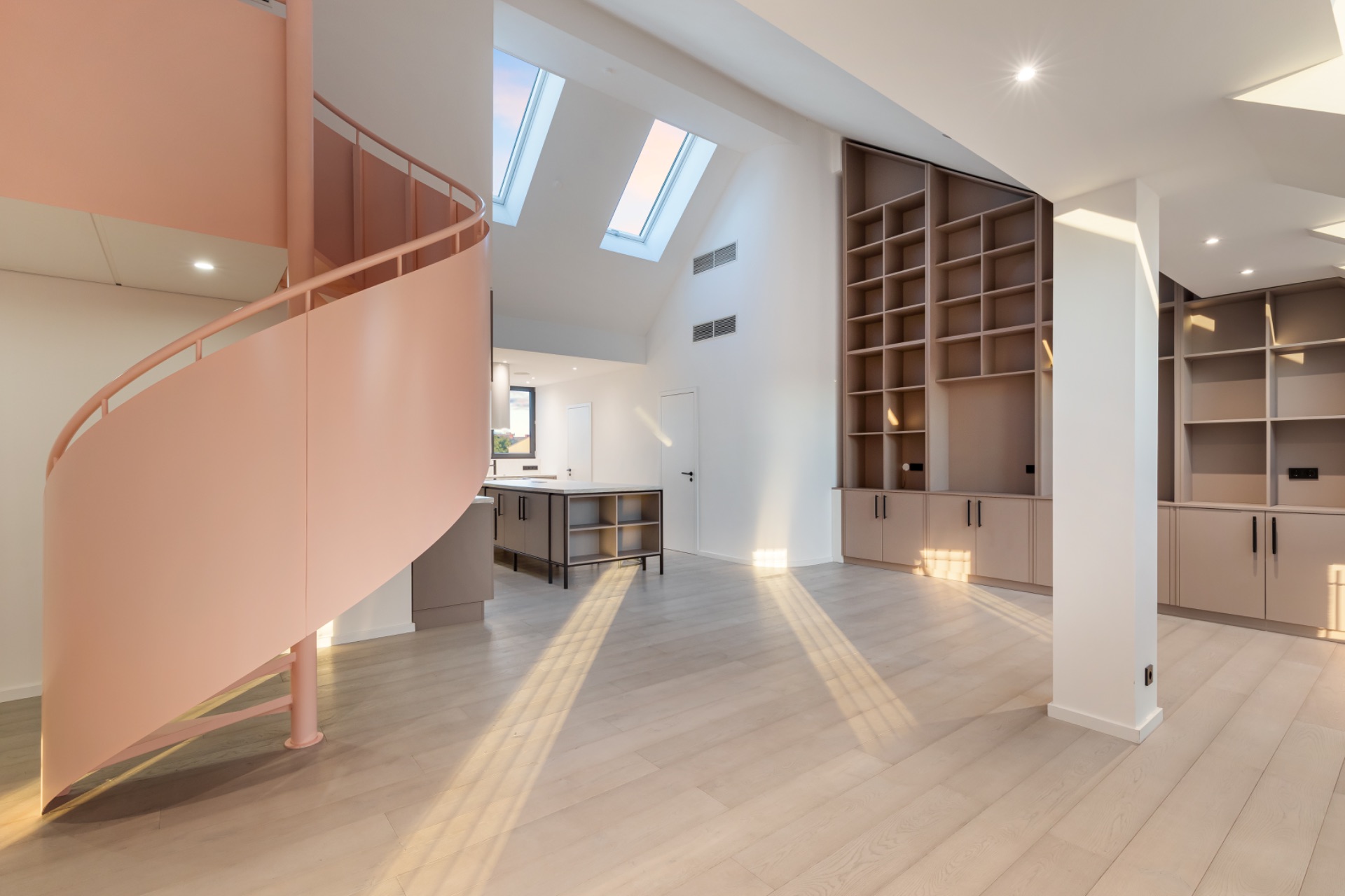 Helles Wohnzimmer mit rosa Wendeltreppe, Einbauregalen und Dachfenstern.