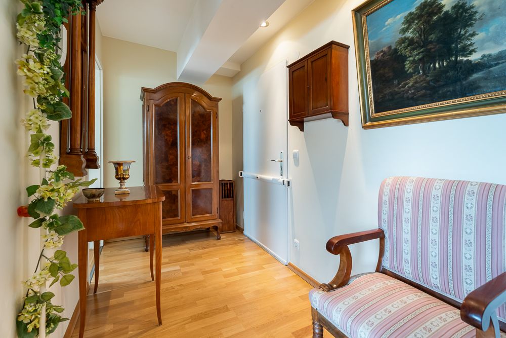 Flur mit Holzmöbeln, dekorativem Spiegel und Gemälde an der Wand.