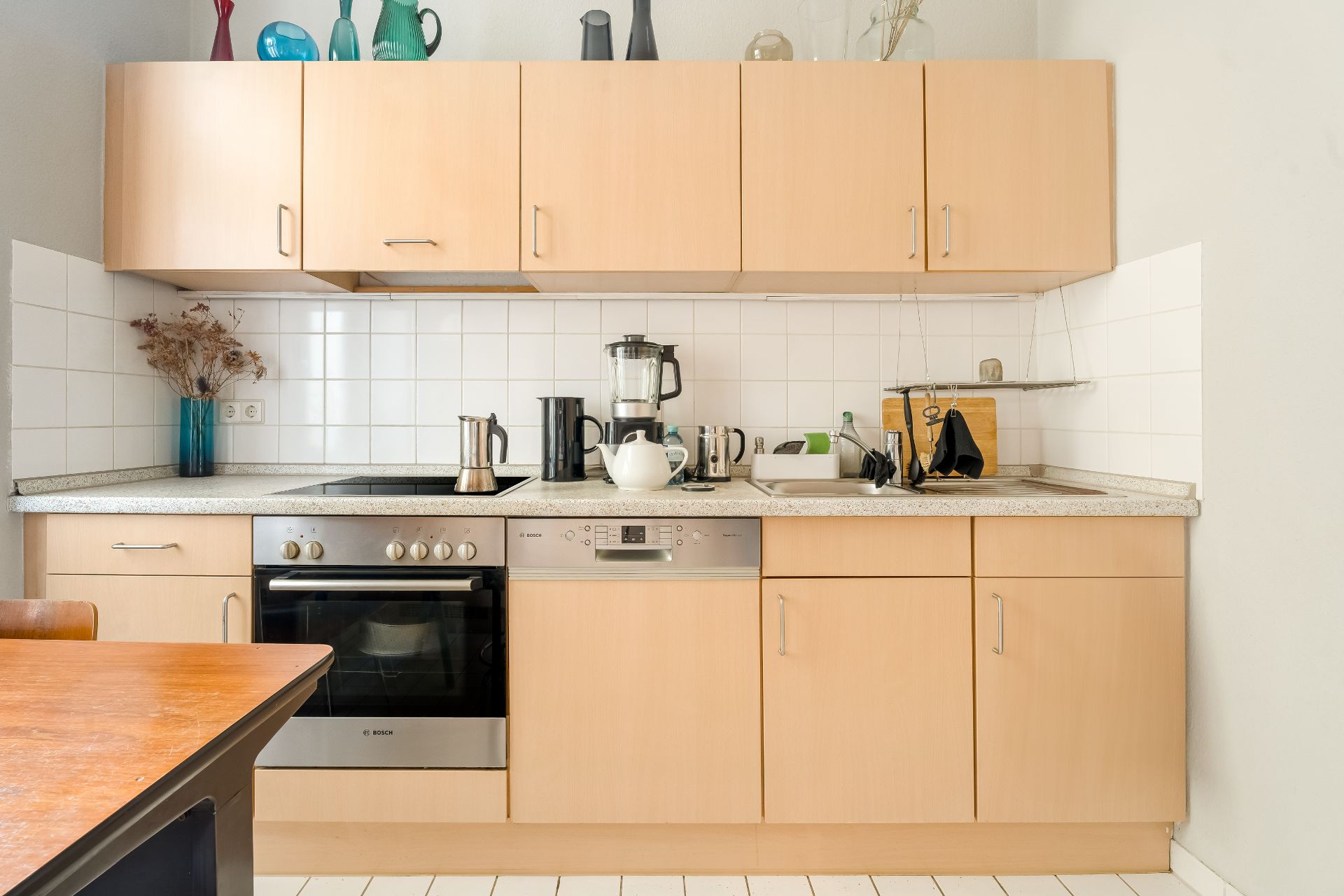 Moderne Einbauküche mit Holzfronten, Herd, Spüle und Küchenutensilien.