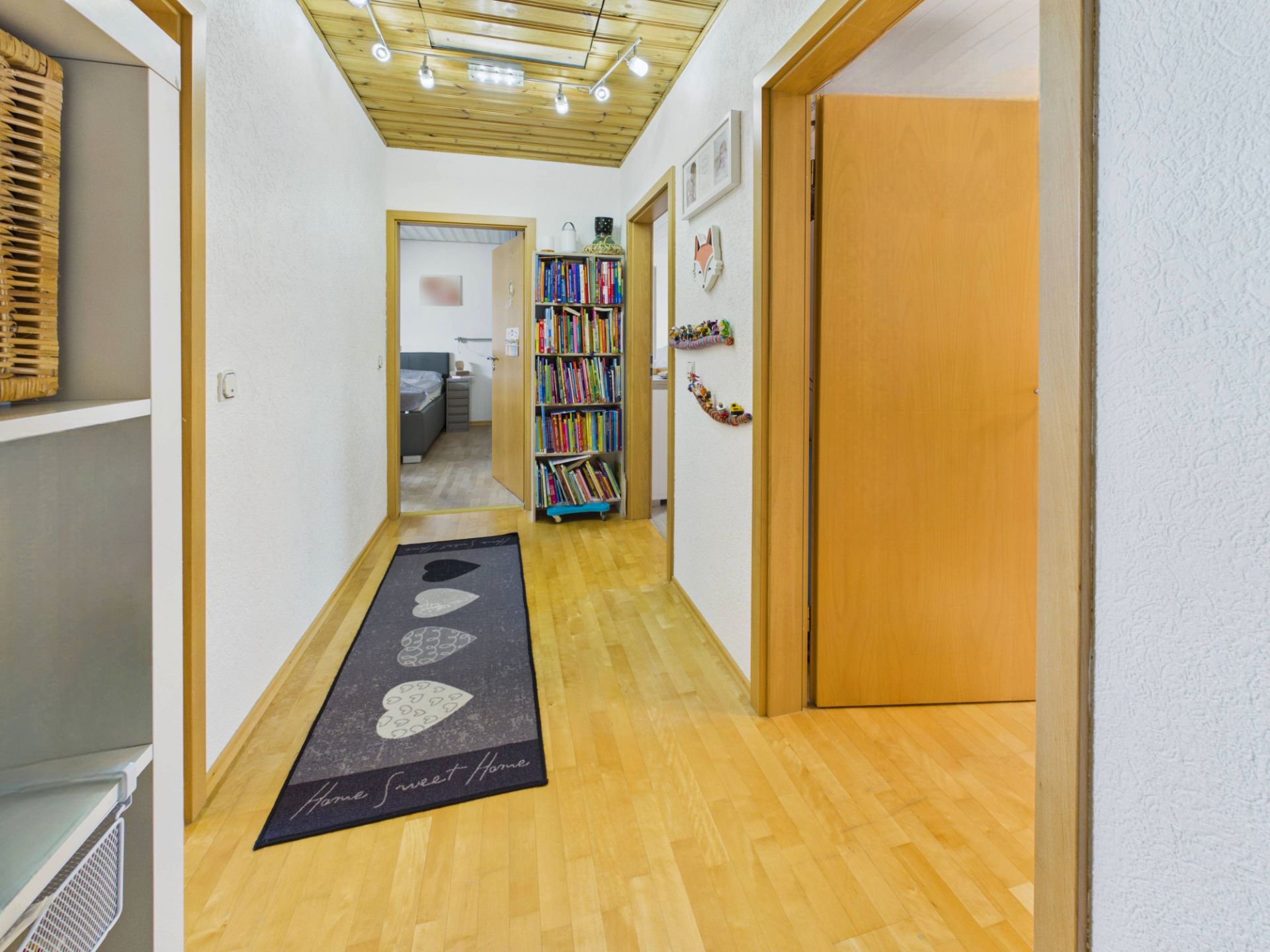 Flur mit Teppichläufer, Bücherregal und sichtbaren Türen zu weiteren Zimmern.