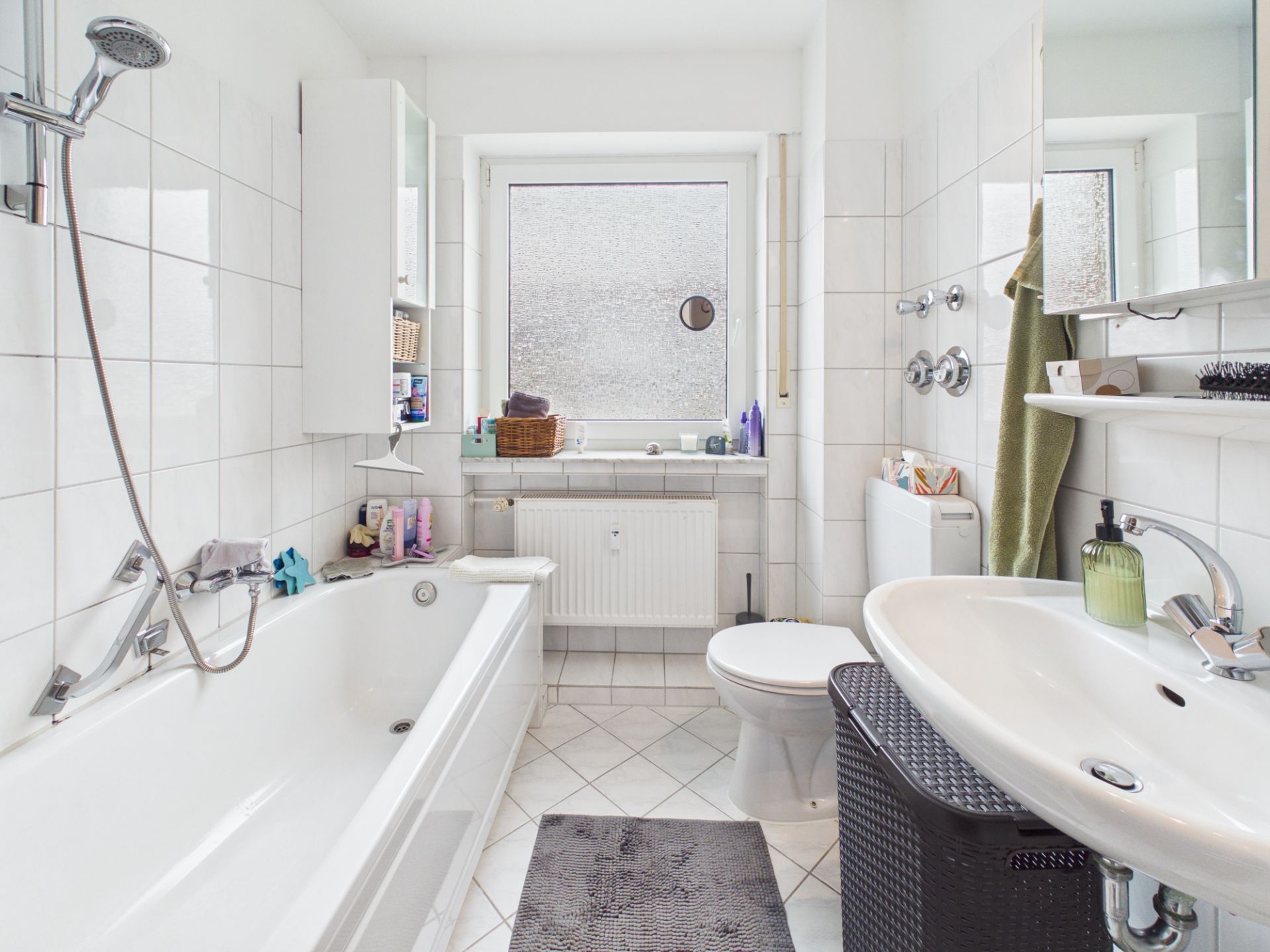 Helles Badezimmer mit Badewanne, Waschbecken, Toilette und großem Fenster.