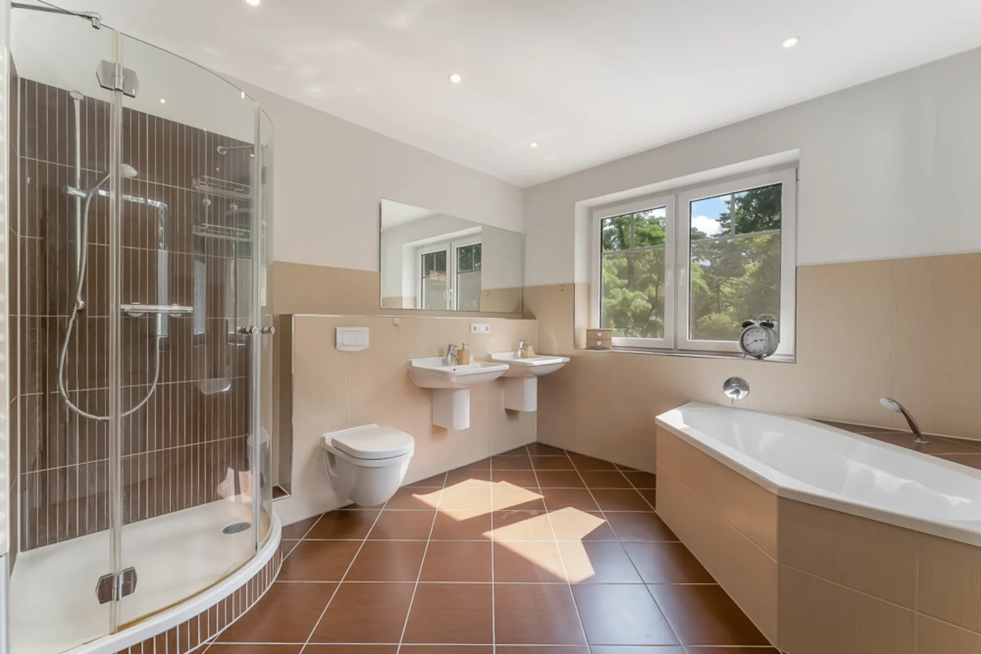 Modernes Badezimmer mit Dusche, Badewanne, zwei Waschbecken und Fenster mit Blick ins Grüne.