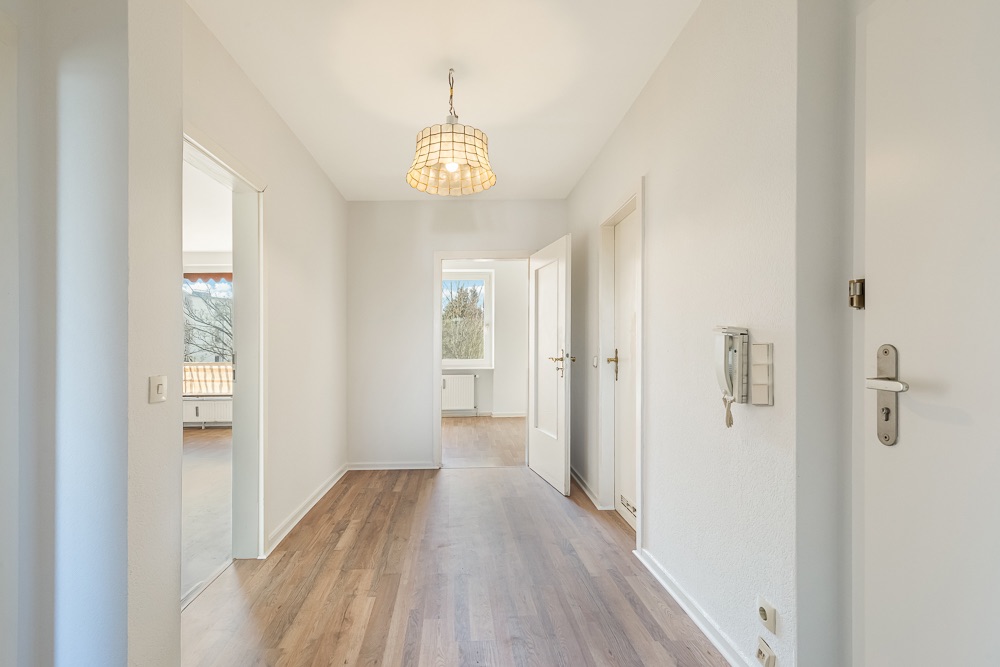 Heller Flur mit Holzboden, mehreren Türen und einer Deckenlampe.