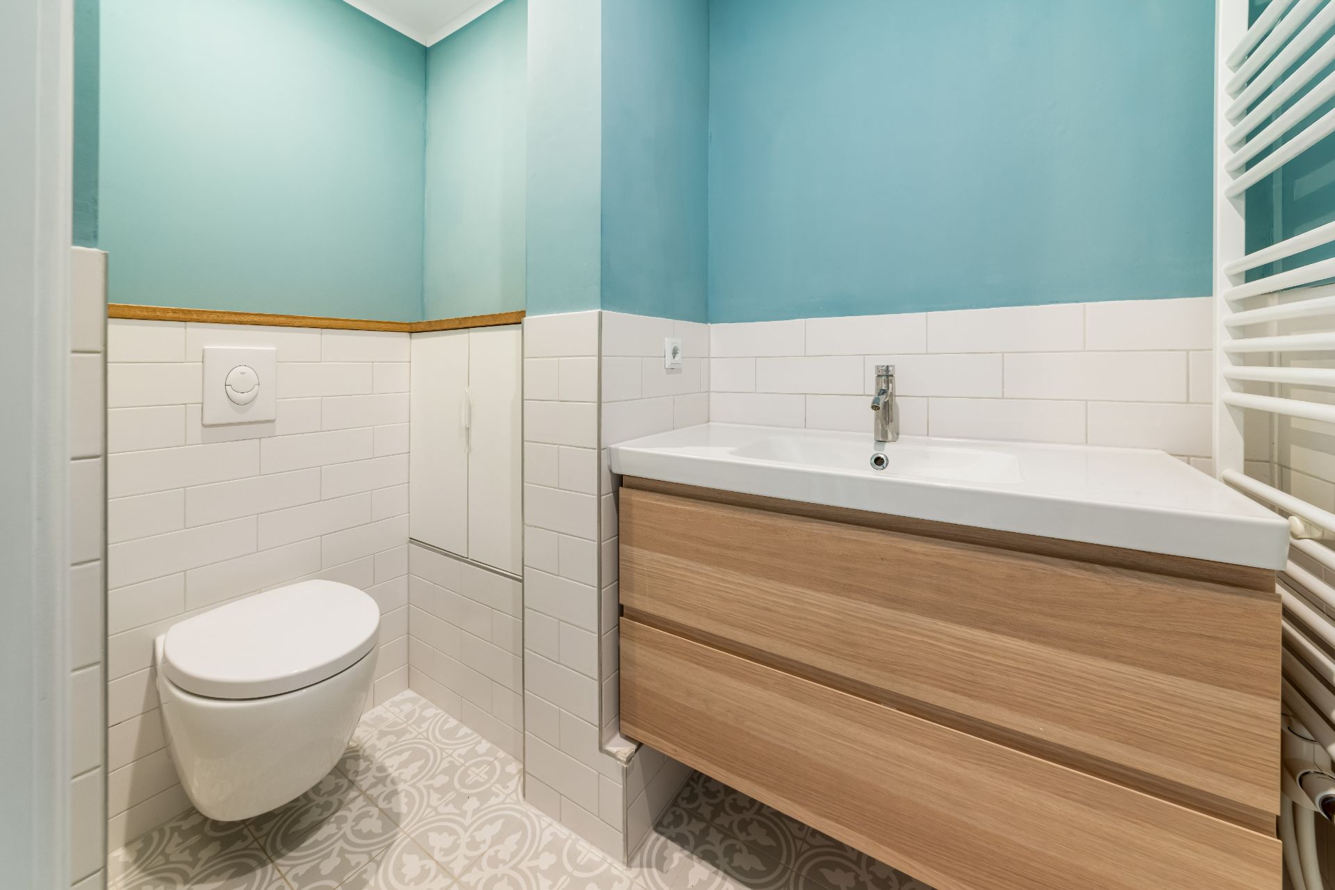 Modernes Badezimmer mit Wandtoilette, Holzwaschtisch und blau-weißen Wänden.