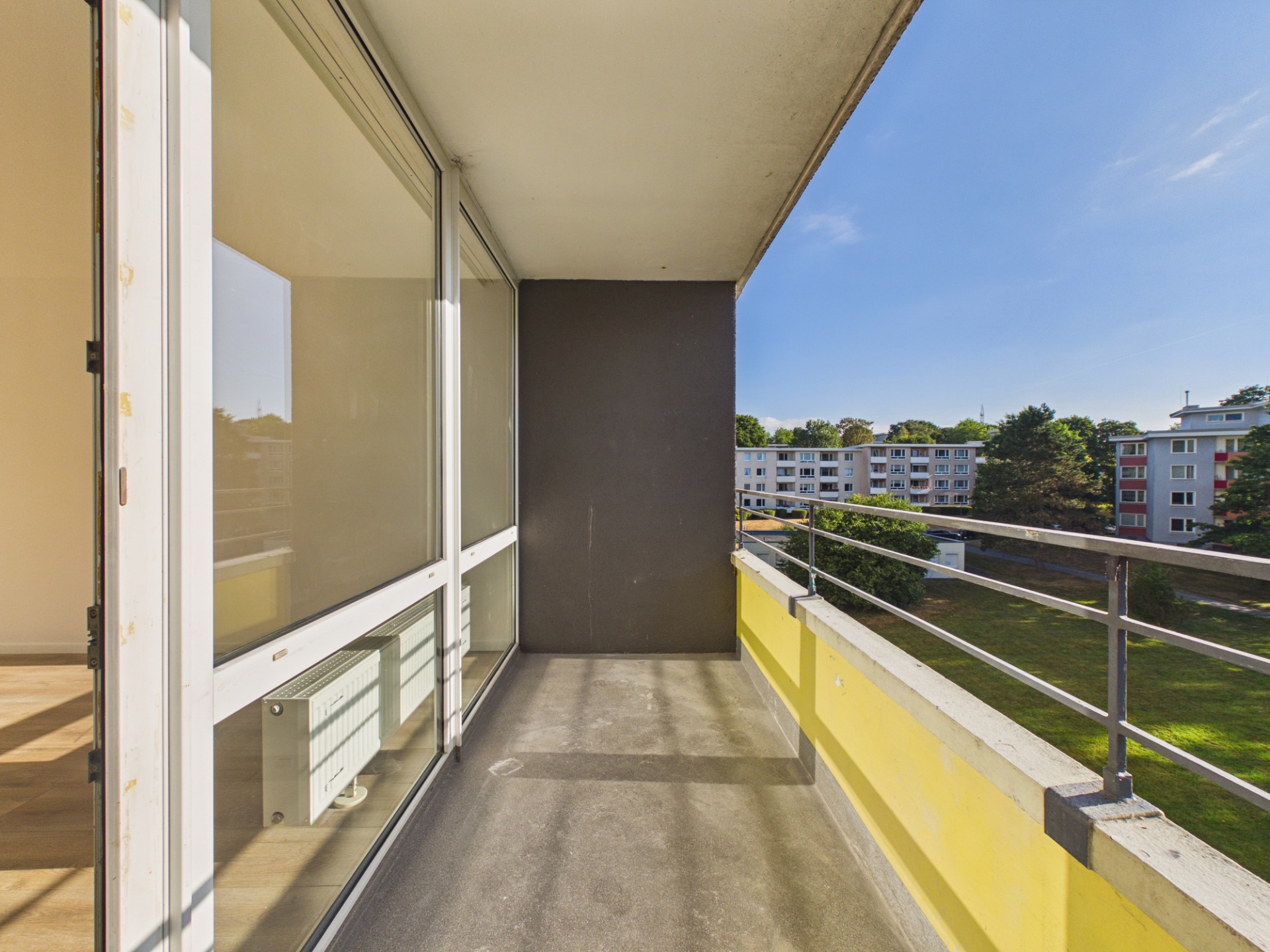 Balkon mit Geländer und Blick auf Wohngebäude sowie grüne Außenanlagen.