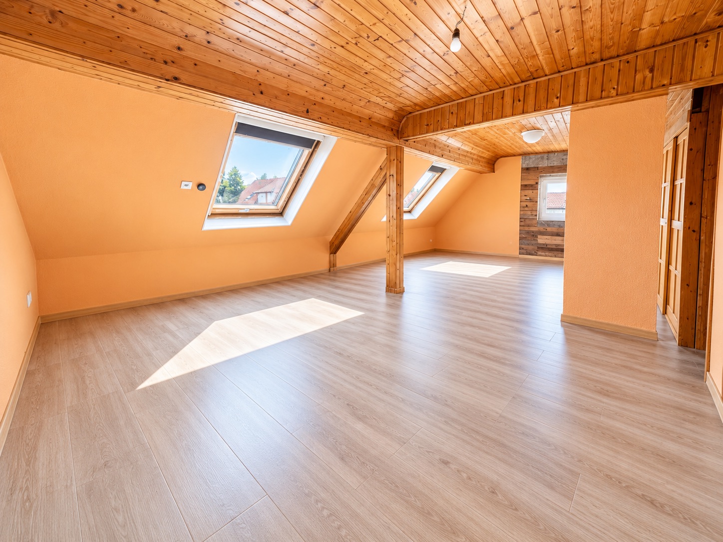 Heller Dachgeschossraum mit Holzdecke, zwei Dachfenstern und hellem Boden.