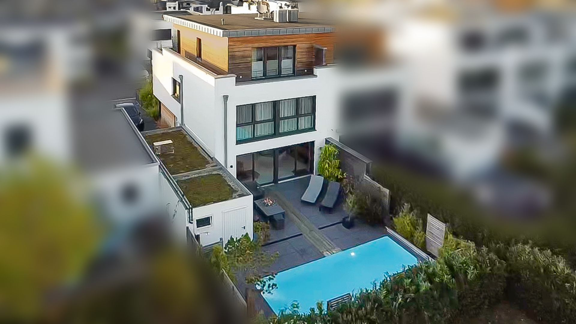 Moderne Wohnhaus mit Terrasse, Liegen und Pool im Garten, aus der Vogelperspektive.