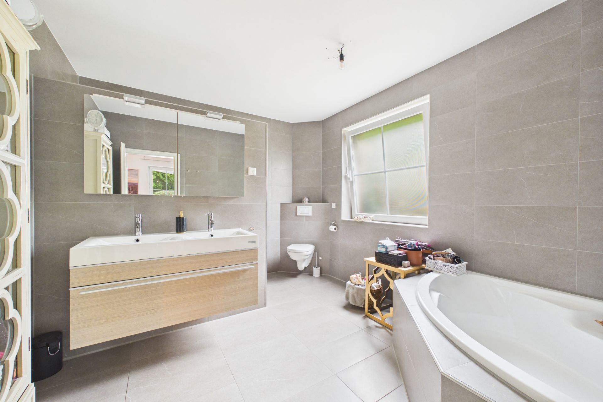 Modernes Bad mit zwei Waschbecken, Eckbadewanne, WC und großem Fenster.