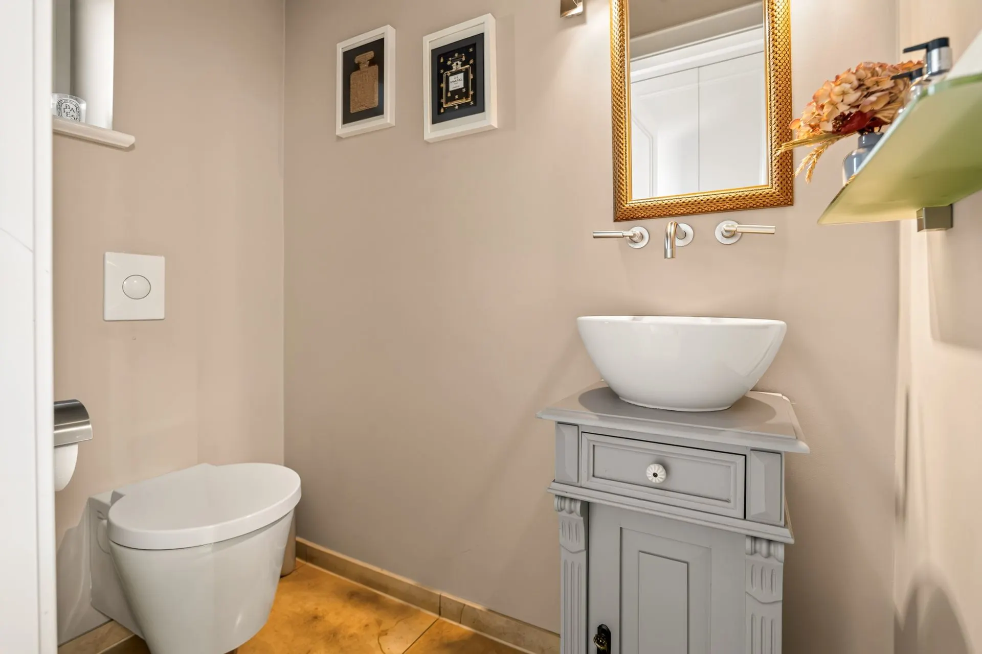 Modernes Bad mit WC, kleinem Waschbecken, Spiegel und Dekoration an der Wand.