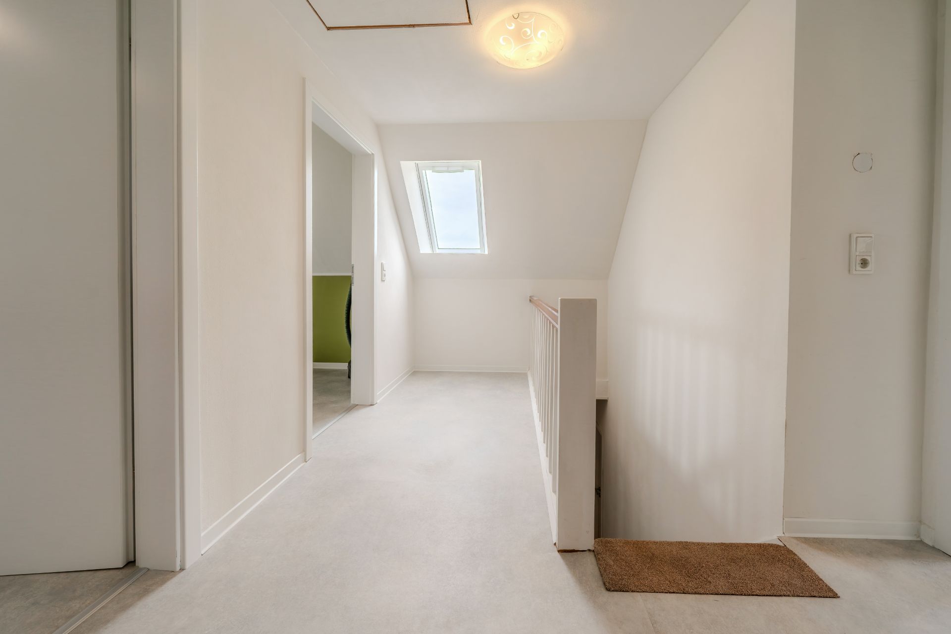 Heller Flur mit Treppe, Dachfenster und Zugang zu einem weiteren Zimmer.