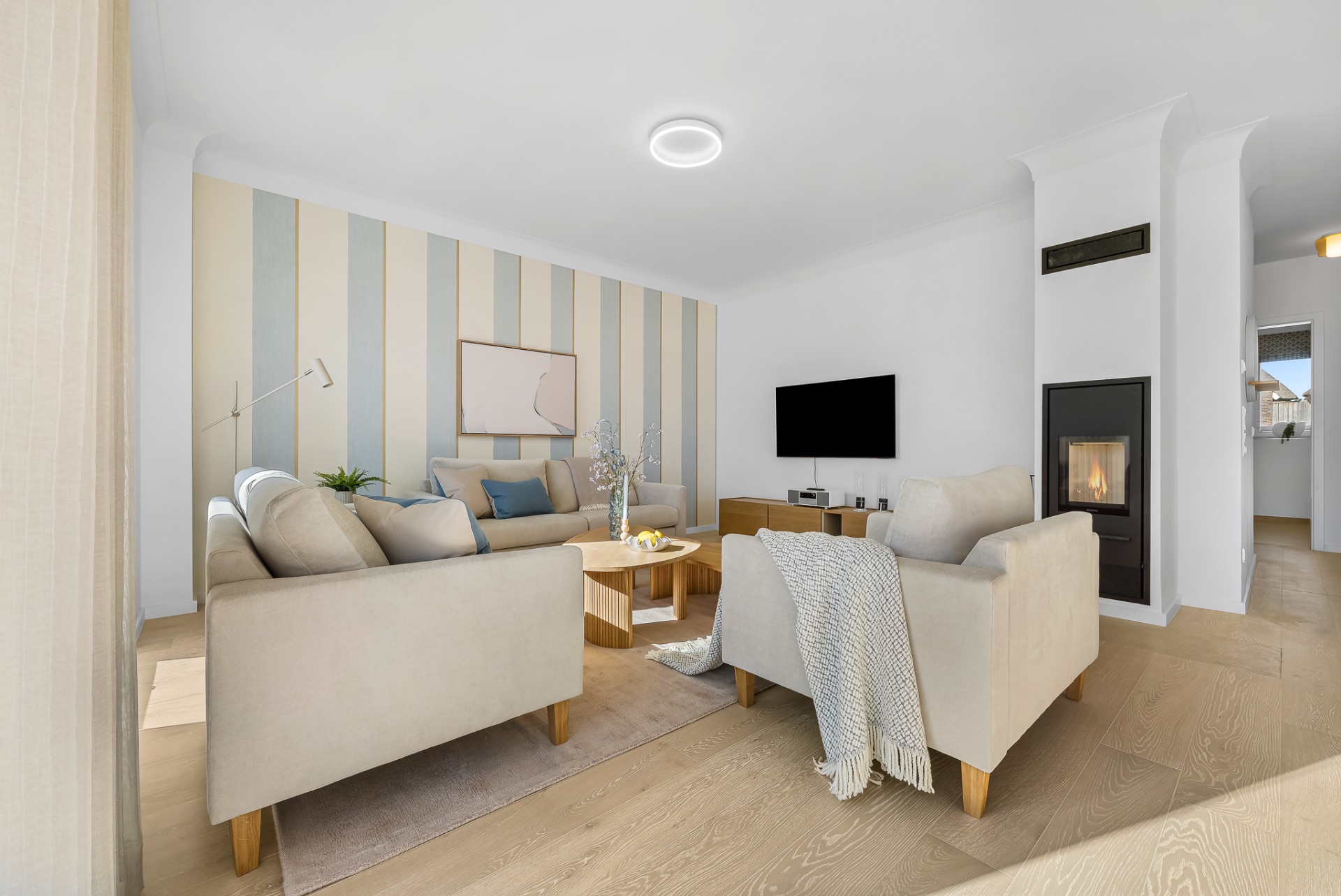 Helles Wohnzimmer mit zwei Sofas, Couchtisch, Fernseher und Kamin auf Holzfußboden.