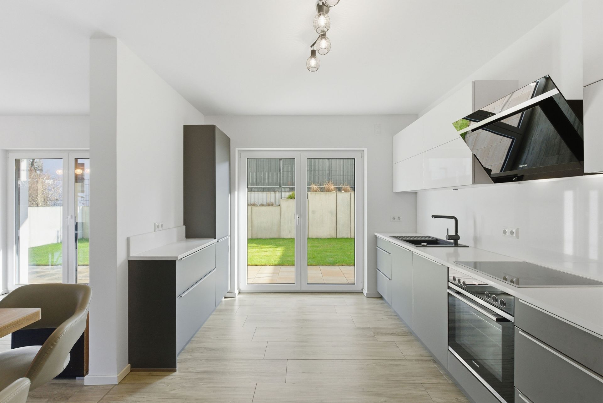 Moderne, helle Küche mit großen Fenstern und Zugang zum Garten.