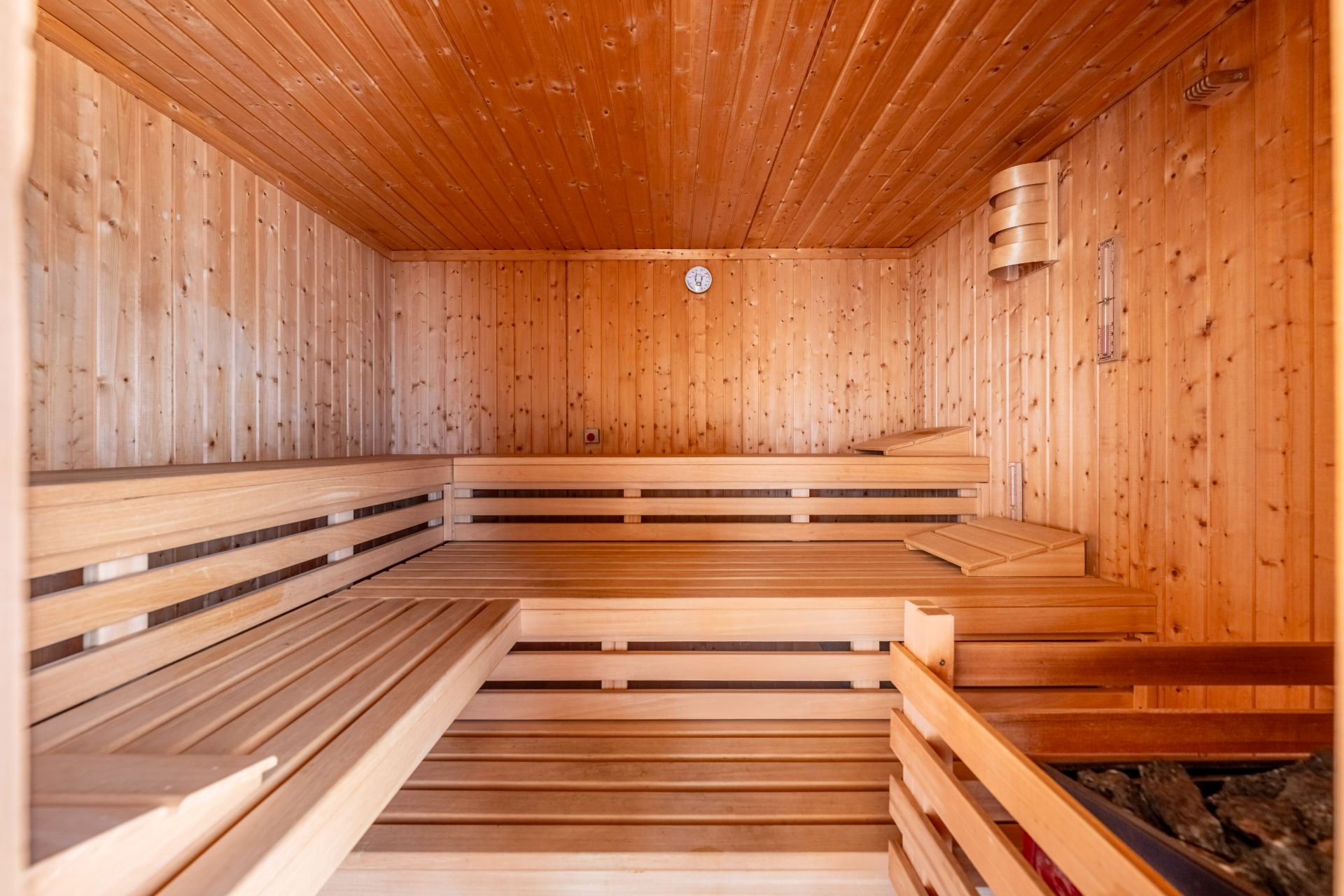 Innenansicht einer Holzsauna mit Holzbänken und einem Saunaofen.