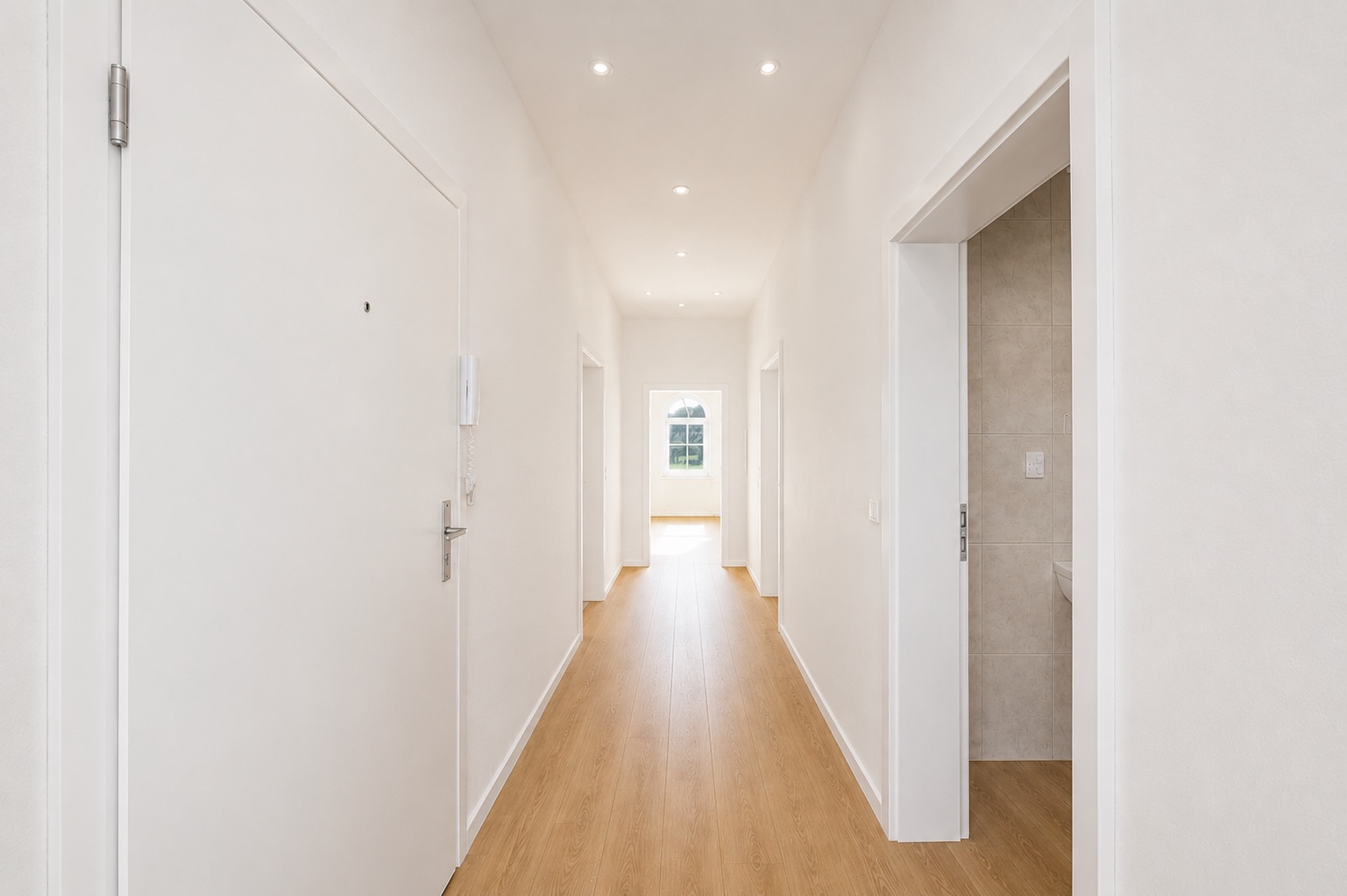 Langer, heller Flur mit Holzboden und mehreren offenen Türen in einer Wohnung.