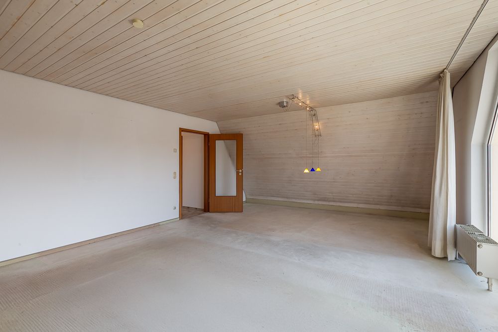 Leerer Raum mit Holzdecke, großem Fenster, Glastür und hängender Lampe.