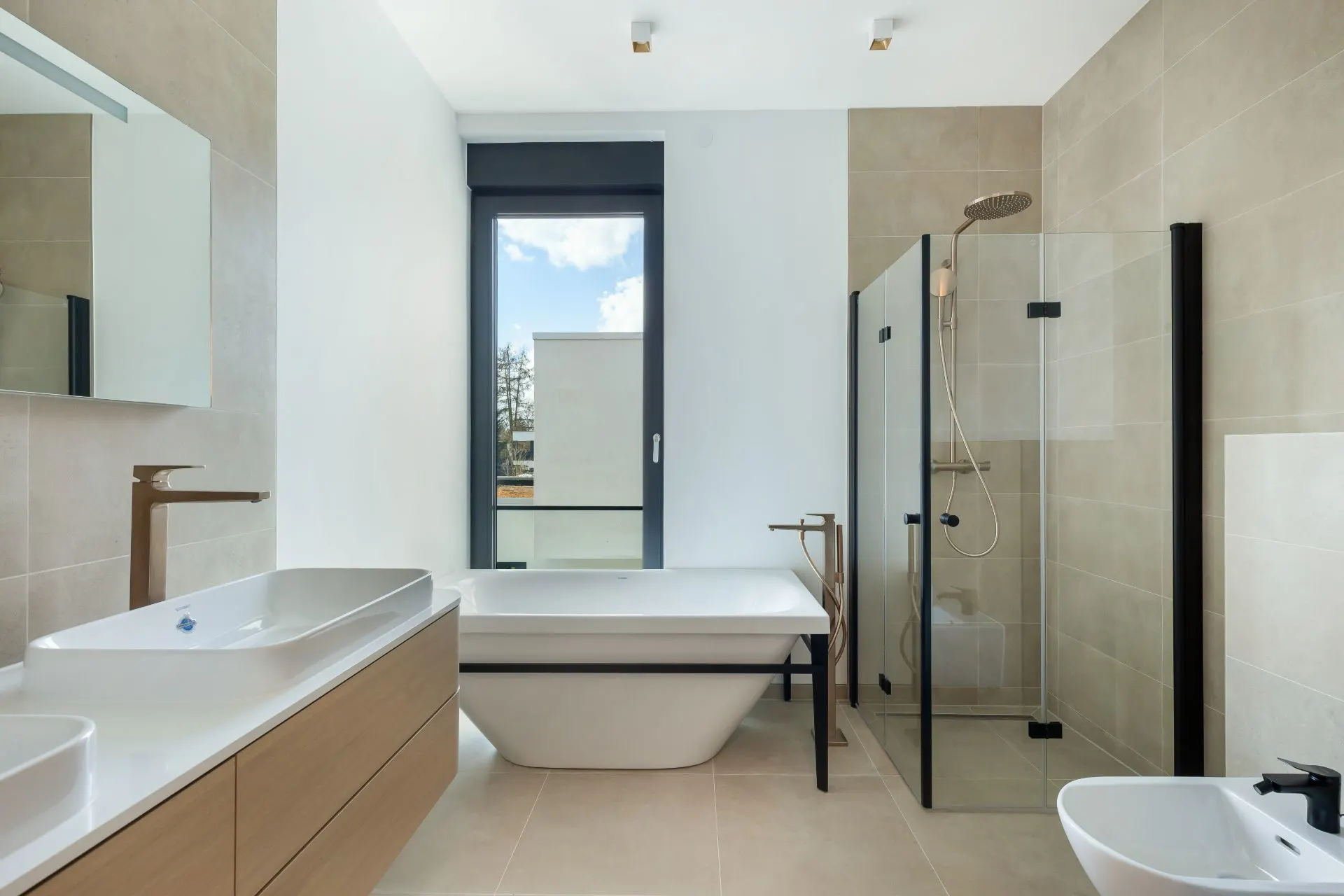 Modernes Badezimmer mit Badewanne, Dusche, Waschbecken und großem Fenster.