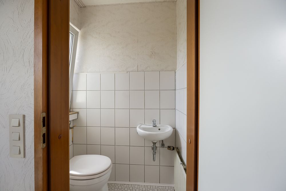 Kleines Badezimmer mit Toilette, Waschbecken und Fenster.