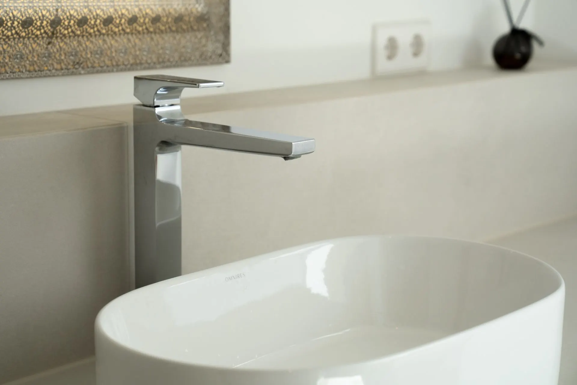 Modernes Waschbecken mit verchromtem Wasserhahn auf einer hellen Arbeitsplatte.