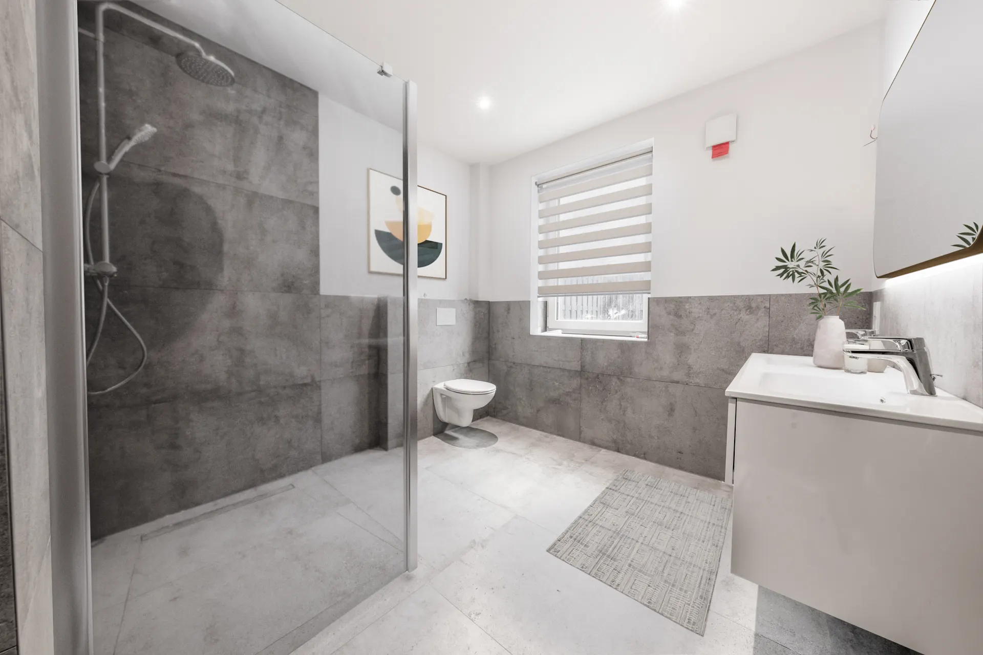 Modernes Badezimmer mit großer Dusche, Wandtoilette, Waschbecken und Fenster mit Jalousie.