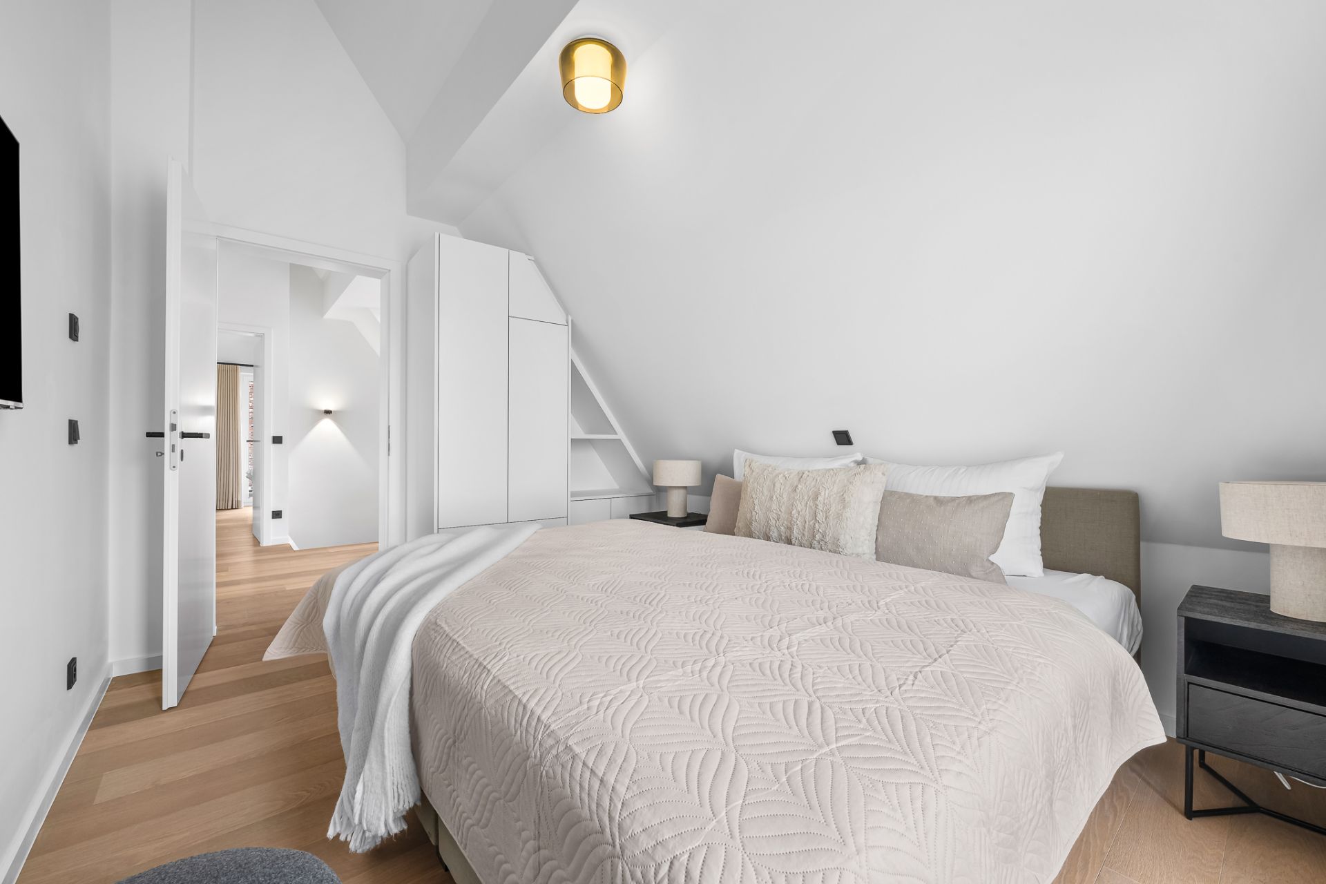 Helles Schlafzimmer mit Doppelbett, Nachttischen, Lampen und Kleiderschrank.