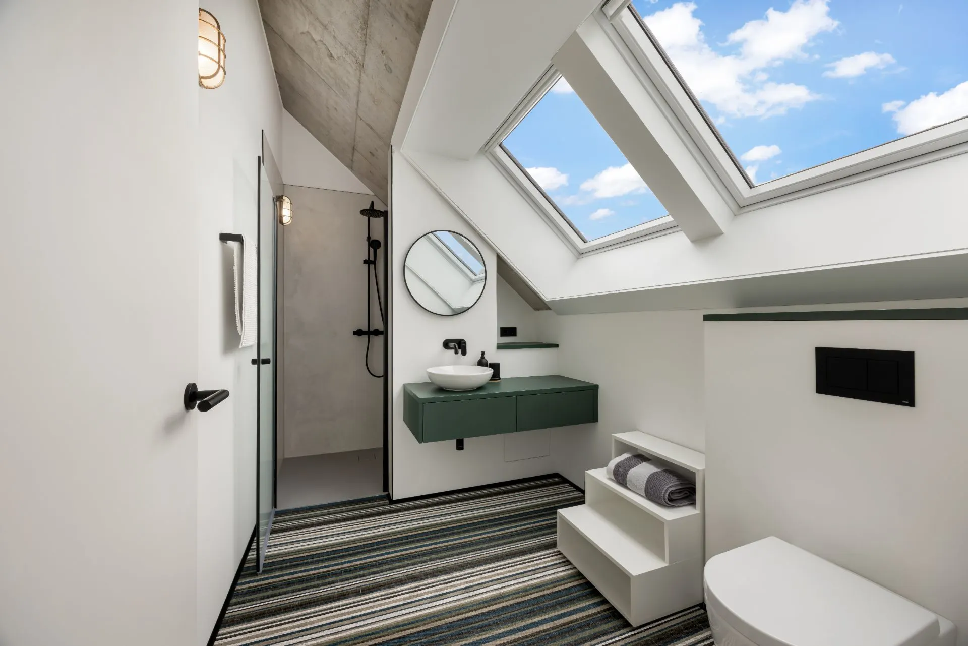 Modernes Badezimmer mit Dachfenster, Waschbecken, Spiegel, Dusche und Toilette.