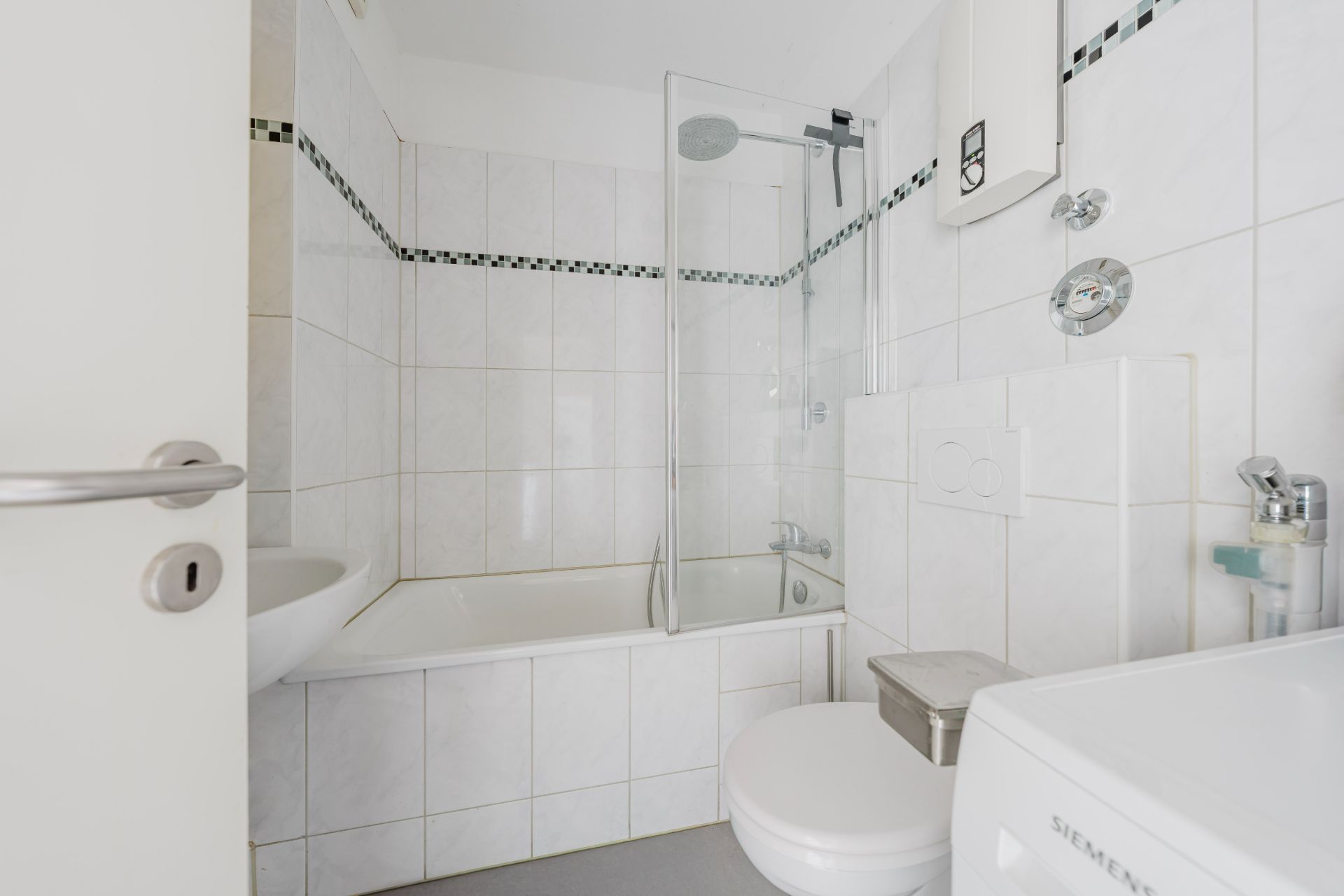 Helles Badezimmer mit Badewanne, Duschtrennwand, WC und Waschbecken.