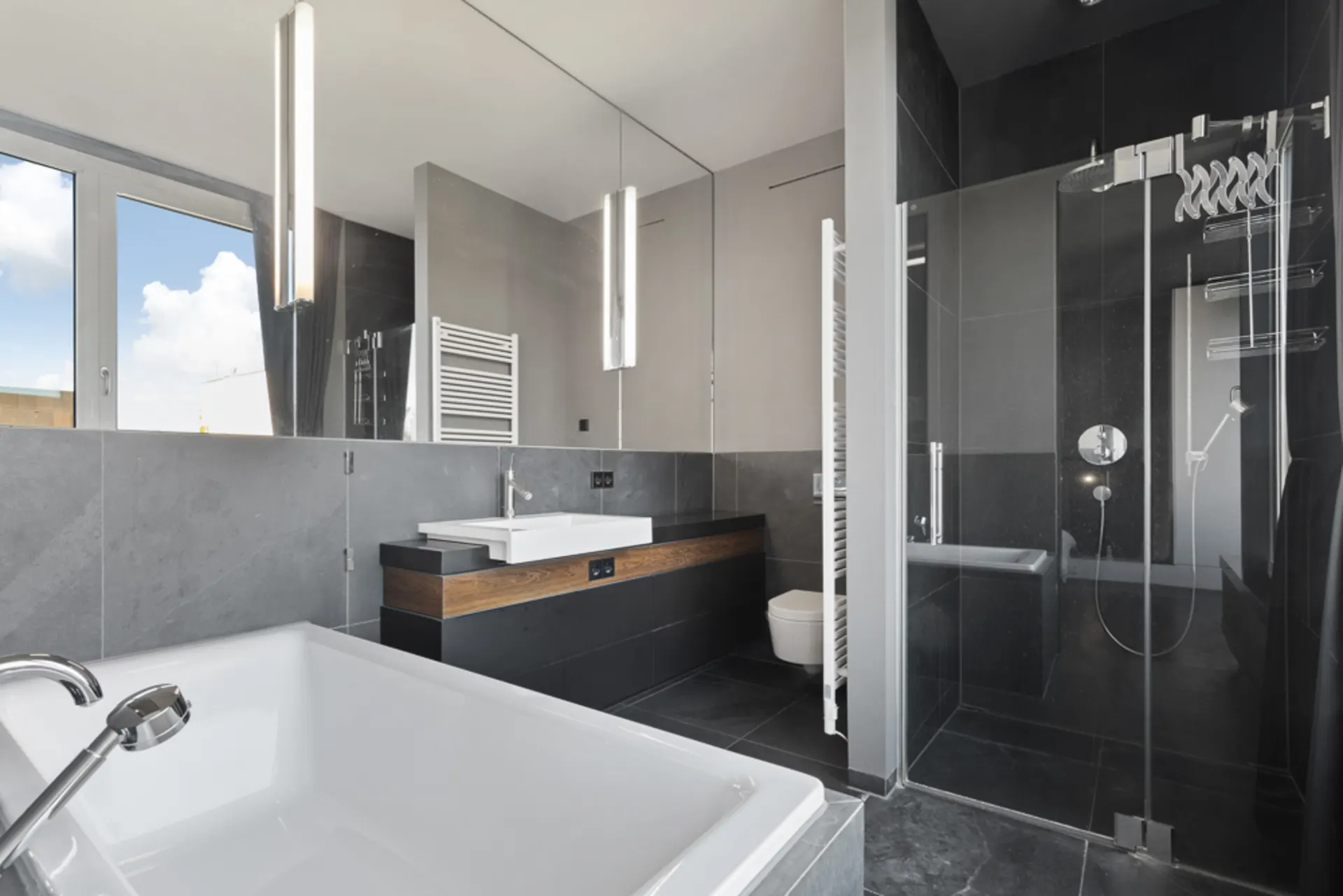Modernes Badezimmer mit Badewanne, Dusche, Waschbecken und Fenster.