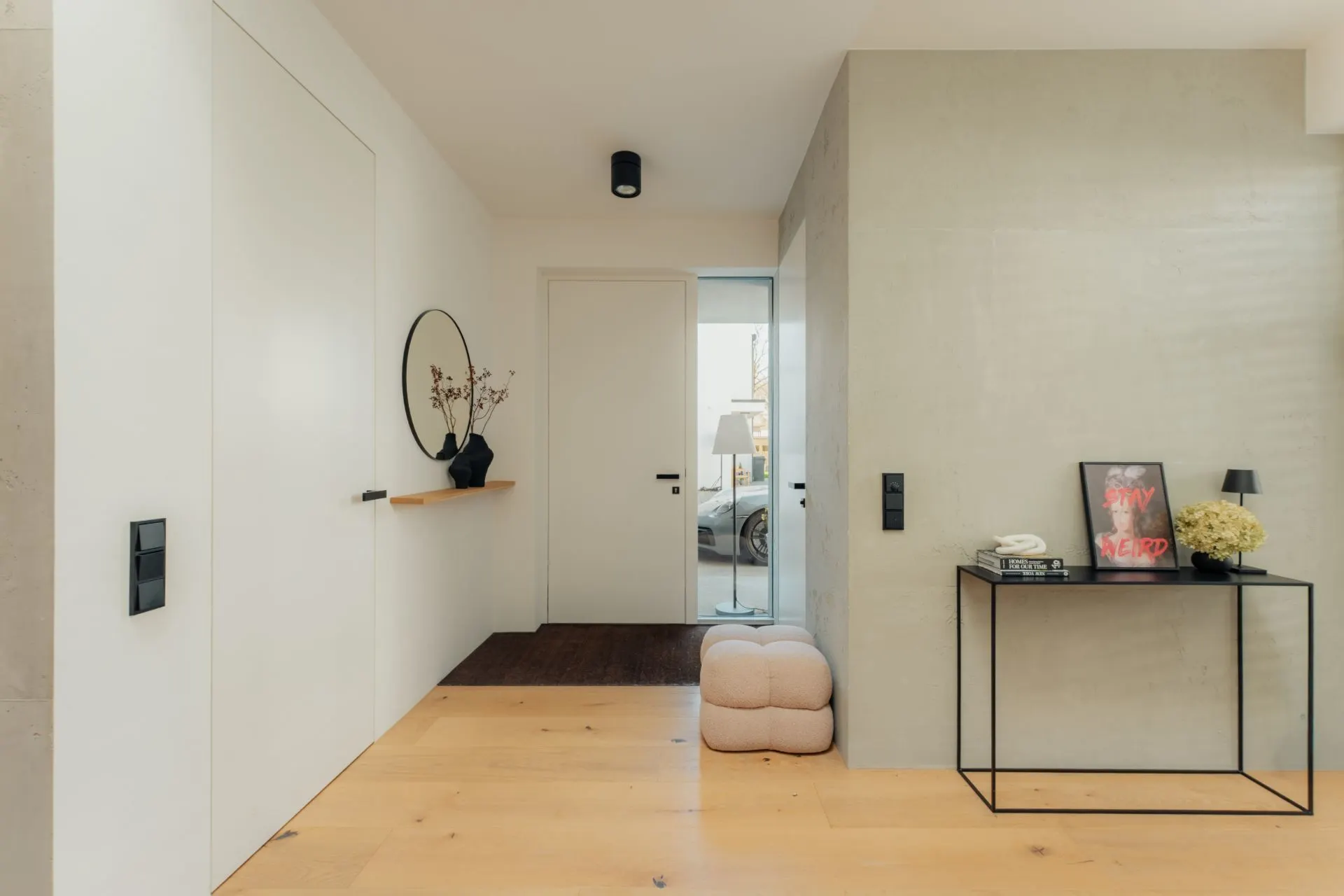 Moderner Flur mit Holzfußboden, Hocker, Konsole und Dekoration an weißer Wand.