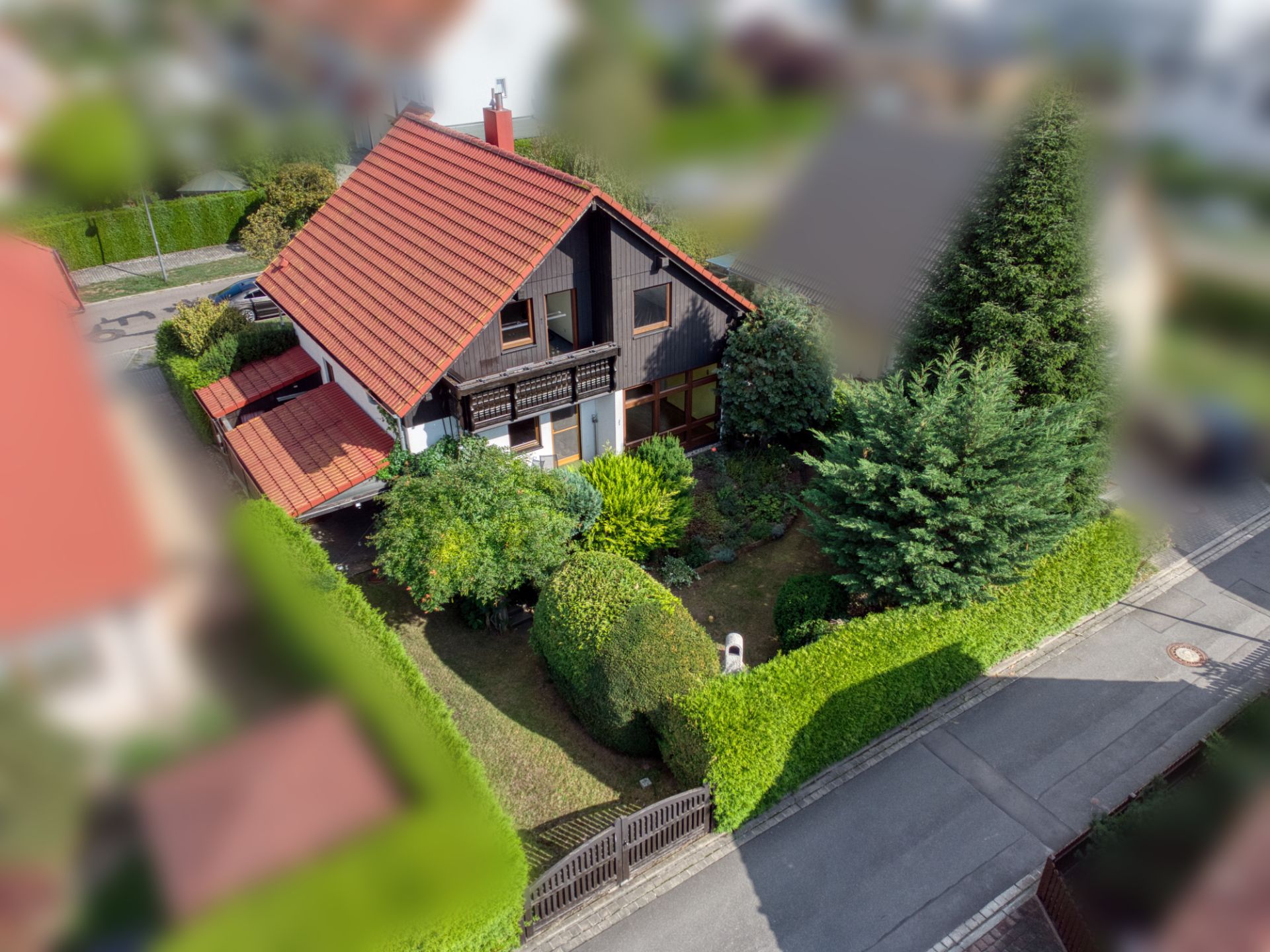 Zweistöckiges Haus mit rotem Dach, Garten und Hecke, von oben fotografiert.