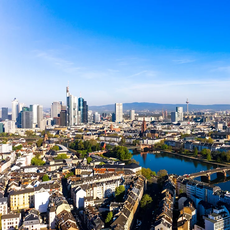 Stadtpanorama mit Fluss, Brücke, Wohnhäusern und Hochhäusern bei klarem Himmel.