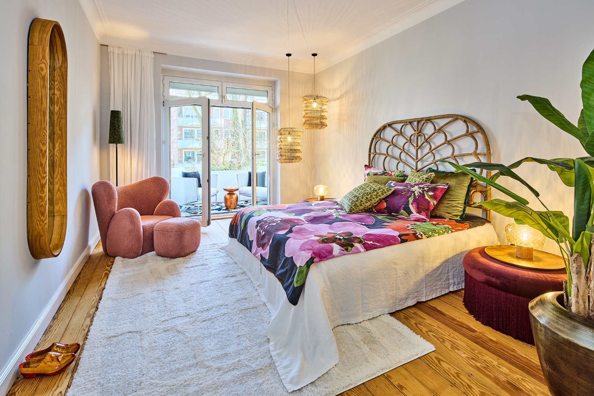 Helles Schlafzimmer mit Doppelbett, Sessel, Teppich und Zugang zu einem Balkon.